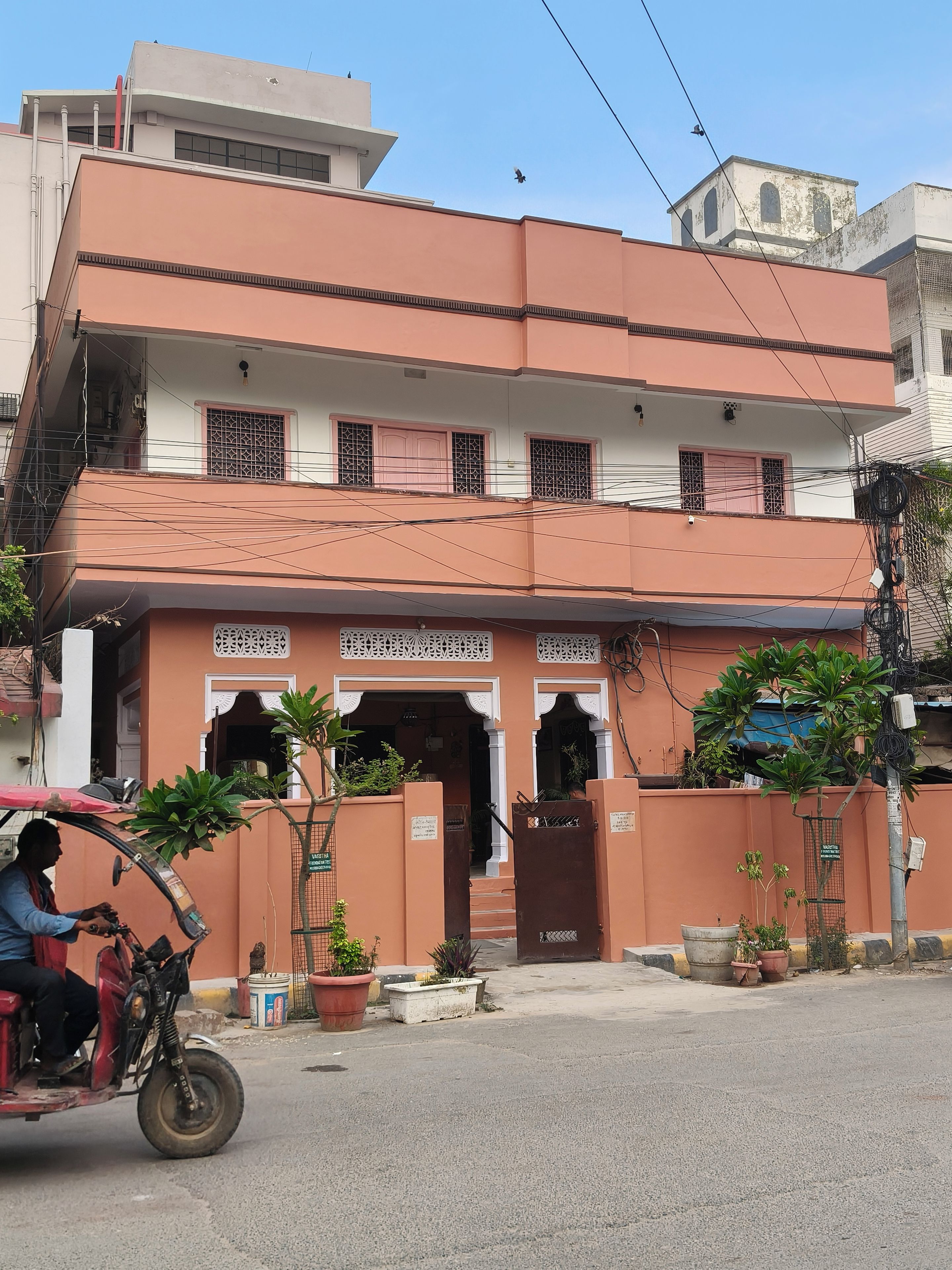 A multi-story building with a gated entrance, potted plants, and a parked motorcycle.