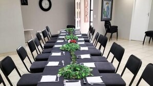A conference room with a long table, black chairs, and a clock on the wall. - Oaklands inn and Conference centre  (Randburg)