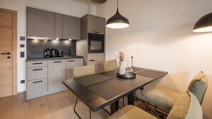 Eine moderne Küche mit grauen Schränken, einem eingebauten Backofen und einem Essbereich mit Tisch und Stühlen.
