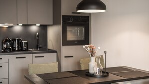 Eine moderne Küche mit Essbereich, inklusive einer Pendelleuchte, einer Blumenvase und einer Kaffeemaschine.