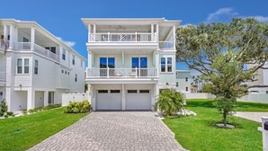 A two-story residential building with a covered front porch, a garage, and a paved driveway.