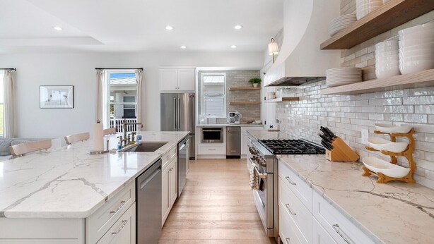 A modern kitchen with a central island, stainless steel appliances, and white cabinetry.