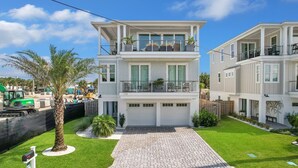A two-story residential building with a balcony, a driveway, and a well-maintained lawn.
