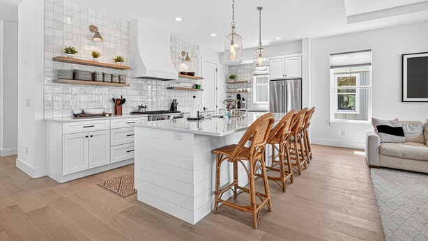 A modern kitchen with white cabinetry, a central island, and bar stools.