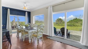 Un comedor con mesa y sillas, ventanas amplias con cortinas y vistas al exterior.