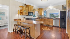 Una cocina moderna con armarios de madera, encimera de granito y una isla integrada con taburetes de bar.