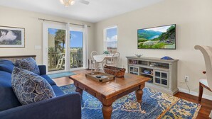 Un salon avec un canapé bleu, une table basse en bois et un téléviseur fixé au mur.