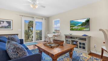 A living room with a blue sofa, a wooden coffee table, and a TV on the wall.