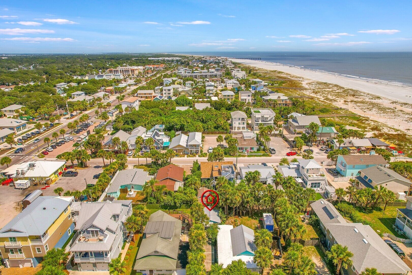A coastal residential area with houses, a beach, and a pier.