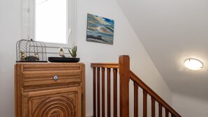 Un aparador de madera con un diseño circular, una jaula para pájaros con un cactus y un cuadro en la pared.