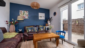 Una sala de estar con un sofá, una mesa de centro de madera y un sillón azul.