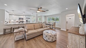 A spacious living area with a sofa, ottoman, and a dining table.