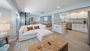 A modern living room with a white sectional sofa, a small coffee table, and a staircase leading to an upper level.
