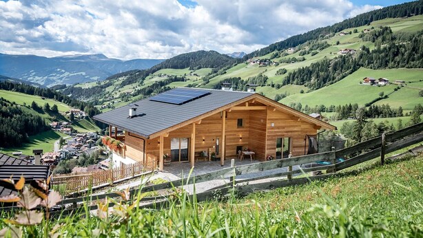 A wooden cabin with a sloped roof and solar panels, surrounded by lush green hills and a clear sky. - Apartment 'Mittermanting' with Mountain View, Private Terrace and Wi-Fi (Villnoss)