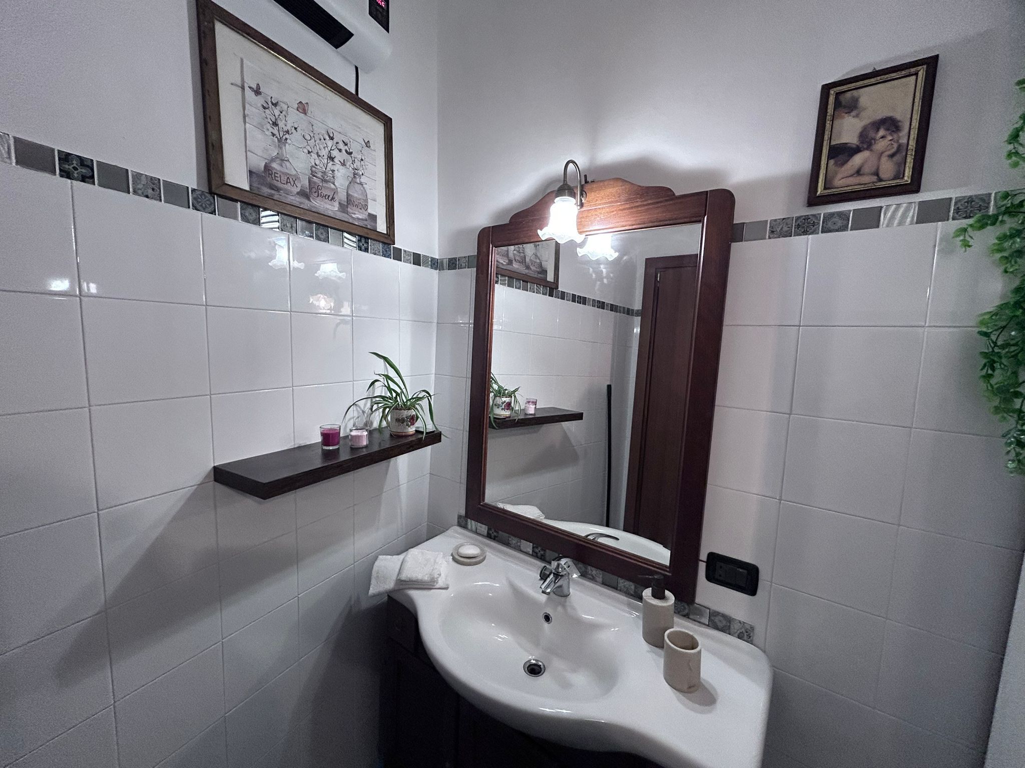 Une salle de bain avec un lavabo blanc, un miroir et une étagère contenant des articles de toilette.