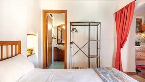 Un dormitorio con cama, armario y baño visible a través de una puerta abierta.
