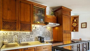 Una cocina con armarios de madera, salpicadero de azulejos y un lavamanos de acero inoxidable.