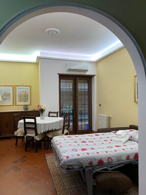 A bedroom with a bed, a dining table with chairs, a small window, and a radiator. - 10 minutes from St. Peter's, Entire apartment in quiet and peaceful area. (Roma)
