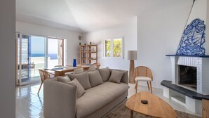 Una sala de estar moderna con un sofá, una mesa de centro y una chimenea. Hay un comedor con una mesa y sillas.