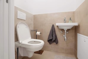 A bathroom with a toilet, sink, towel rack, and a small rug.