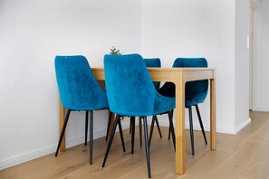 Un coin repas avec une table en bois et quatre chaises bleues aux pieds noirs.