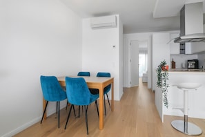 A modern kitchen with white cabinets, a wooden dining table with blue chairs, and a white bar stool.