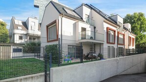 A modern residential building with a flat roof, large windows, and a fenced yard. - Superior Cityline Suite (Vienna)