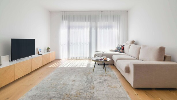 A modern living room with a flat-screen TV, a beige sofa, a small round coffee table, and a wooden cabinet. - Superior Cityline Suite (Vienna)
