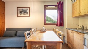 Une pièce chaleureuse avec une table à manger en bois, un canapé et une fenêtre donnant sur une forêt.