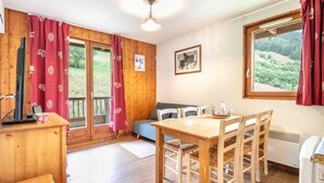 Une pièce chaleureuse avec une table en bois, des chaises, un canapé et un téléviseur.