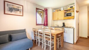 Un espace de vie compact comprenant un canapé, une table à manger, des chaises, une kitchenette équipée d’un four à micro-ondes et d’un petit réfrigérateur.