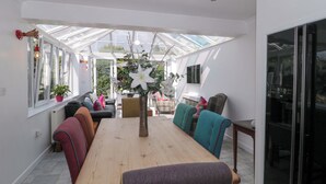 A conservatory with a dining table, chairs, and a sofa.
