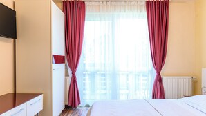 A hotel room with a bed, a desk, a wardrobe, and a television. - Tranquil 1-bedroom house in Bușteni (Bușteni)