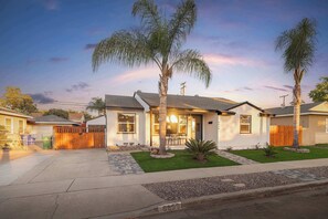 A residential house with a garage, a front yard with palm trees, and a clear sky.