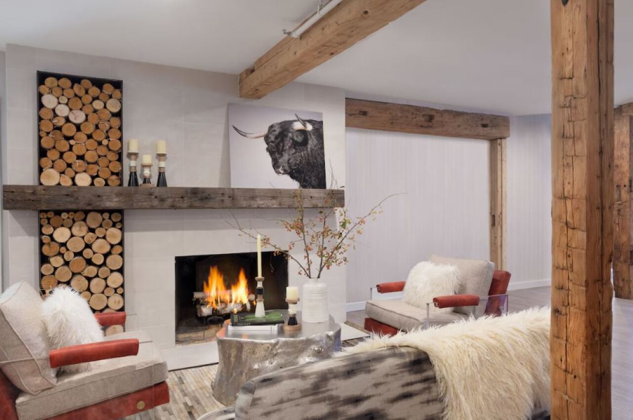 Ein modernes Wohnzimmer mit Kamin, Holzscheiten, einem aufgehängten Stierkopf-Kunstwerk und einer gemütlichen Sitzecke.