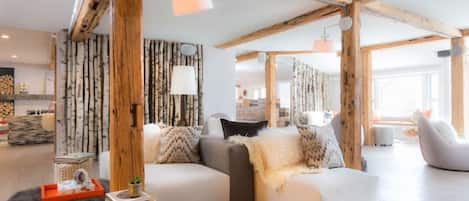 Een moderne woonkamer met een houten plafond, een zithoek en een pluizig vloerkleed.