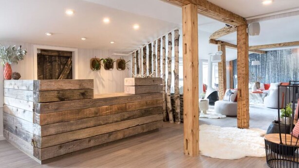 A wooden reception desk with a modern interior, including a white wall and a large window. - Enjoy Nature & Town | Stay in Style at Field Guide Lodge, Close to Everything (Stowe)