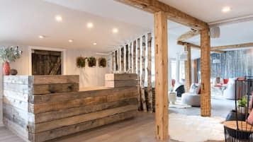A wooden reception desk with a modern interior, including a white wall and a large window.