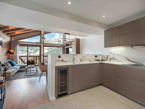 Cozinha moderna com bancada de mármore, armários de madeira e uma janela ampla com vista para o exterior.