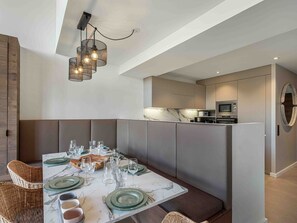 Uma cozinha moderna com eletrodomésticos embutidos e uma área de jantar com mesa de mármore posta para seis pessoas.