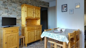 Ein Essbereich mit Steinwand, Holzkästen, einem Fernseher und einem Tisch mit Stühlen.