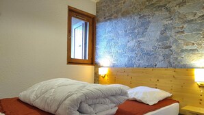Ein Bett mit weißer Bettwäsche, einer roten Decke und einem hölzernen Kopfteil.