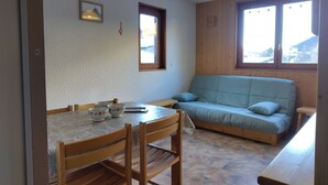 Ein gemütliches Zimmer mit Esstisch, Stühlen, einer Couch und einem Fenster mit Blick.