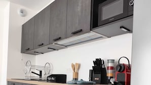 Une cuisine moderne avec des meubles gris, un four en acier inoxydable et un four à micro-ondes.