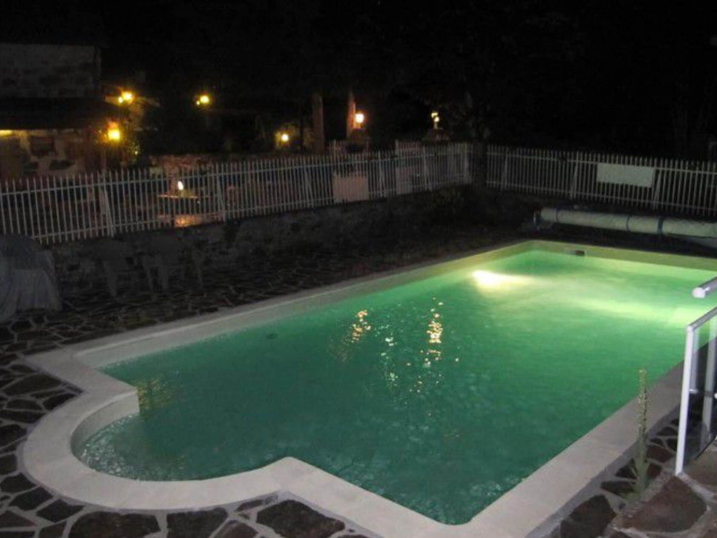 Ein Schwimmbecken mit Steinrand und einem kleinen Wasserspiel im Eck.