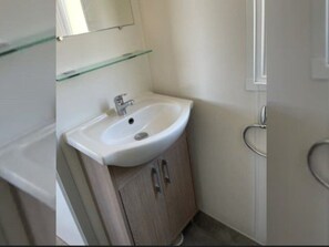Ein Badezimmer mit einem weißen Waschbecken, einem Spiegel darüber und einem Holzschrank darunter.