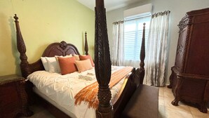 A four-poster bed with a wooden headboard, a wooden nightstand, and a wooden wardrobe. - Solar-powered Gem Tours Walk to Beaches Eats (San Juan)