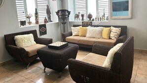 A living room with wicker furniture, a coffee table, and decorative items on shelves. - Solar-powered Gem Tours Walk to Beaches Eats (San Juan)