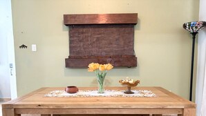 A wooden table with a vase of yellow flowers, a small bowl, and a decorative item on a placemat. - Solar-powered Gem Tours Walk to Beaches Eats (San Juan)