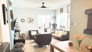 A living room with a wooden bench, two sofas, a dining table, and a ceiling fan. - Solar-powered Gem Tours Walk to Beaches Eats (San Juan)